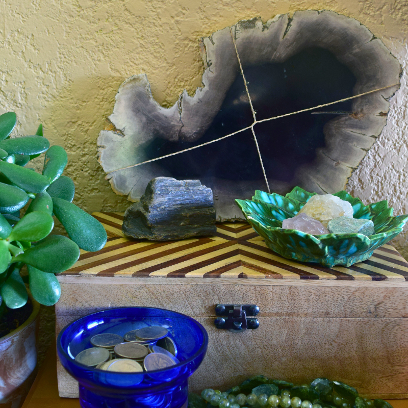 Feng Shui Wealth Area A Reason 4 Being wood box with rocks and crystals on top behind a blue glass bowl with coins